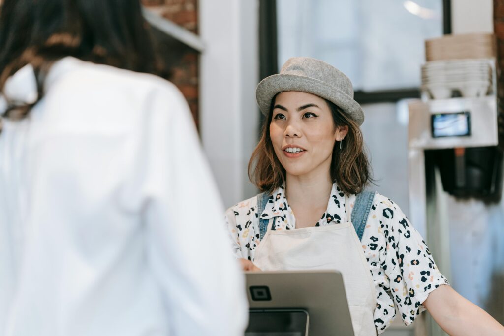 Interaction chaleureuse en caisse Une femme à la caisse sourit et échange avec un client dans un magasin.
